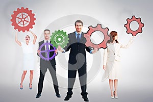 Composite image of business people holding cogs