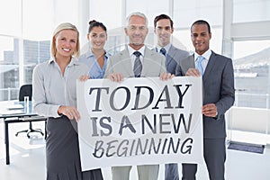 Composite image of business team holding large blank poster