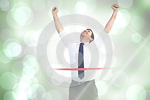 Composite image of businessman celebrating success with arms up