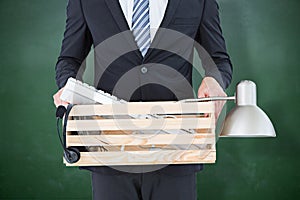 Composite image of businessman holding box of his things