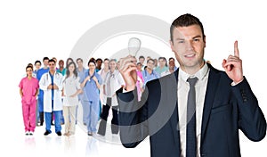 Composite image of businessman holding light bulb and pointing