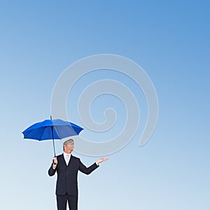 Composite image of businessman holding umbrella with hand out