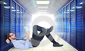 Composite image of businessman lying on the floor while reading a book