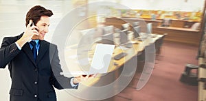 Composite image of businessman making a phone call while using a laptop