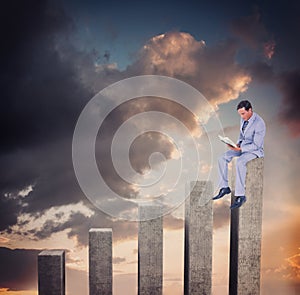 Composite image of businessman reading book while sitting over white background