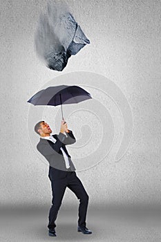 Composite image of businessman sheltering under black umbrella