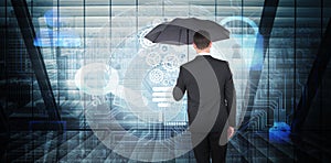 Composite image of businessman sheltering under black umbrella