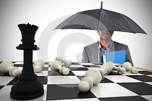 Composite image of businessman standing under umbrella