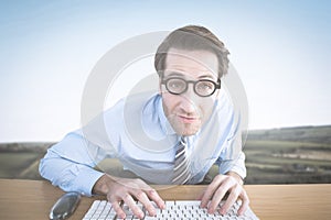 Composite image of businessman typing on his keyboard wearing glasses