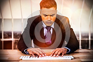 Composite image of businessman typing on keyboard at desk