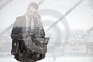 Composite image of businessman using laptop while phoning