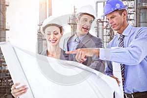 Composite image of businessmen and a woman with hard hats and holding blueprint