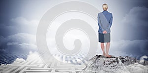 Composite image of businesswoman standing with hands behind back