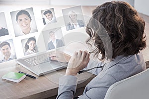 Composite image of businesswoman using laptop at desk in creative office