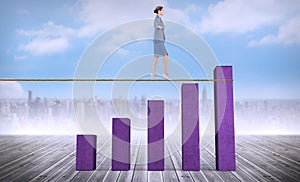 Composite image of businesswoman walking tightrope