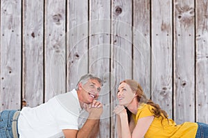 Composite image of casual couple lying on floor