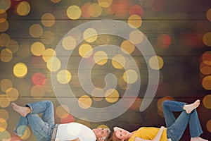 Composite image of casual couple lying on floor