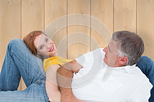 Composite image of casual couple lying on floor