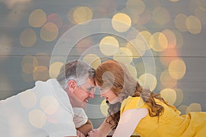 Composite image of casual couple lying on floor with piggy bank