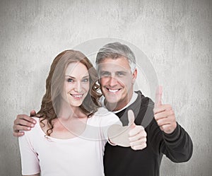 Composite image of casual couple showing thumbs up