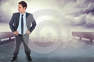 Composite image of cheerful businessman standing with hands on hips