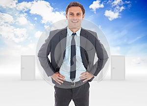 Composite image of cheerful businessman standing with hands on hips