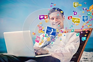 Composite image of cheerful young businessman lying on a deck chair with his computer