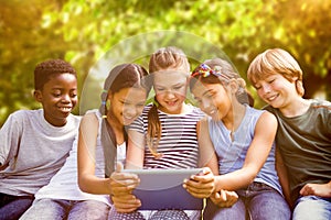 Composite image of children using digital tablet at park