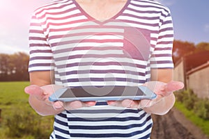 Composite image of close up of man holding tablet against rural landscape