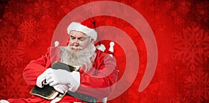 Composite image of close-up of santa claus holding bible while sleeping on chair