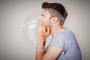 Composite image of close up side view of man blowing nose