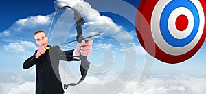 Composite image of concentrated businessman shooting a bow and arrow