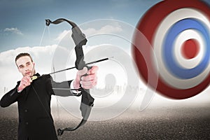 Composite image of concentrated businessman shooting a bow and arrow