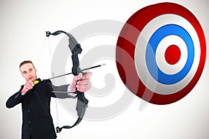 Composite image of concentrated businessman shooting a bow and arrow