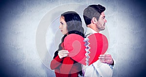 Composite image of couple back to back holding heart halves