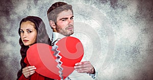 Composite image of couple back to back holding heart halves