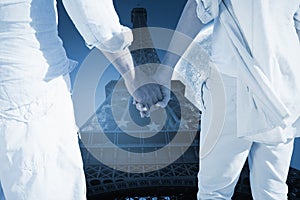 Composite image of couple on the beach looking out to sea holding hands