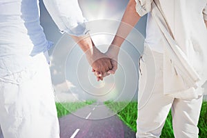 Composite image of couple on the beach looking out to sea holding hands