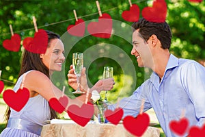 Composite image of couple with champagne flutes sitting at outdoor cafÃÂ©