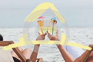 Composite image of couple clinking glasses of cocktail on beach