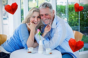 Composite image of couple drinking coffee and hearts 3d