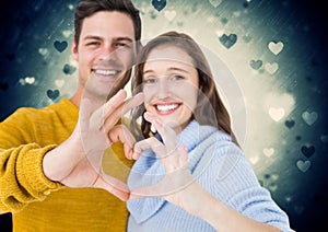 Composite image of couple forming heart shape with hands