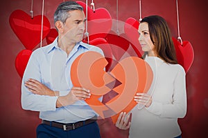 Composite image of couple holding broken heart shape paper 3d