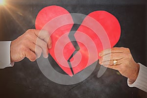 Composite image of couple holding a broken paper heart