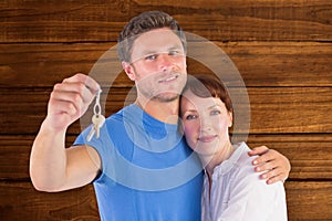 Composite image of couple holding keys to home