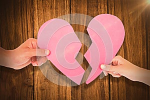 Composite image of couple holding two halves of broken heart