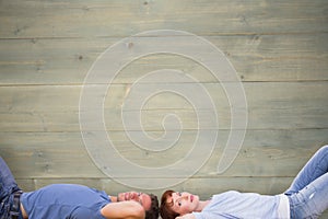 Composite image of couple lying on the floor