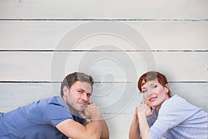 Composite image of couple lying on the floor