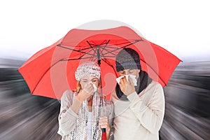 Composite image of couple in winter fashion sneezing under umbrella