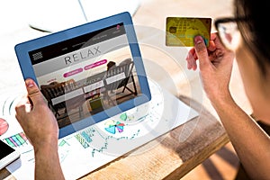 Composite image of cropped image of hipster businessman using tablet and credit card